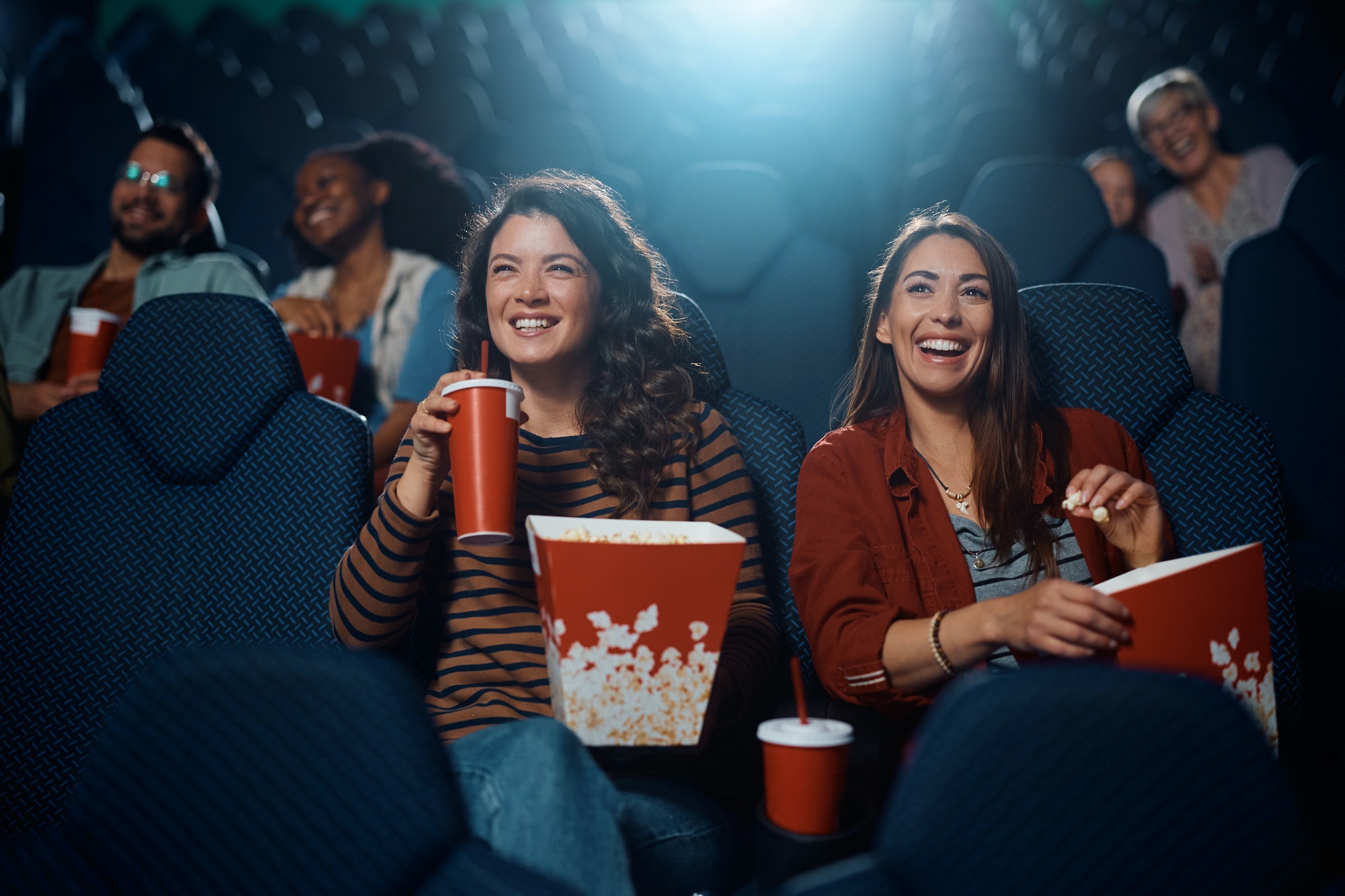 Young happy women watching movie in cinema.