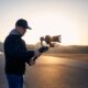 Young man filming with camera and gimbal. Filmmaker standing against city at sunrise. Prague, Czech